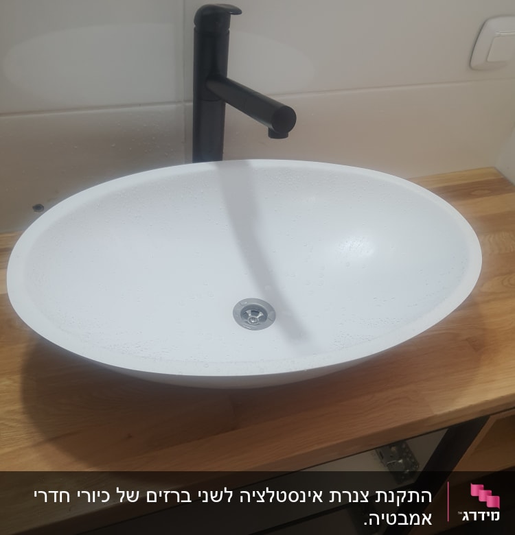 כיור לבן עם ברז שחור על משטח עץ